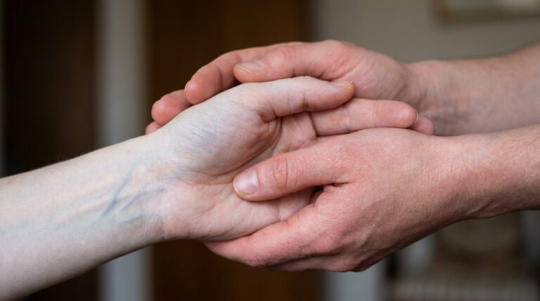 Une personne tient doucement la main d'une autre personne pour la réchauffer.