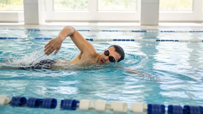 Nageur effectuant une longueur de crawl dans une piscine intérieure lumineuse