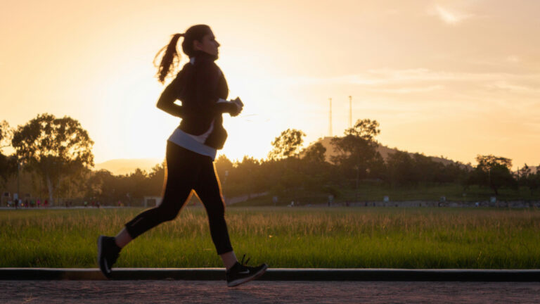 Une femme court dans un parc au coucher du soleil.