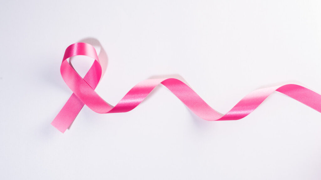 Un ruban rose posé sur une table représentant la lutte contre le cancer du sein.